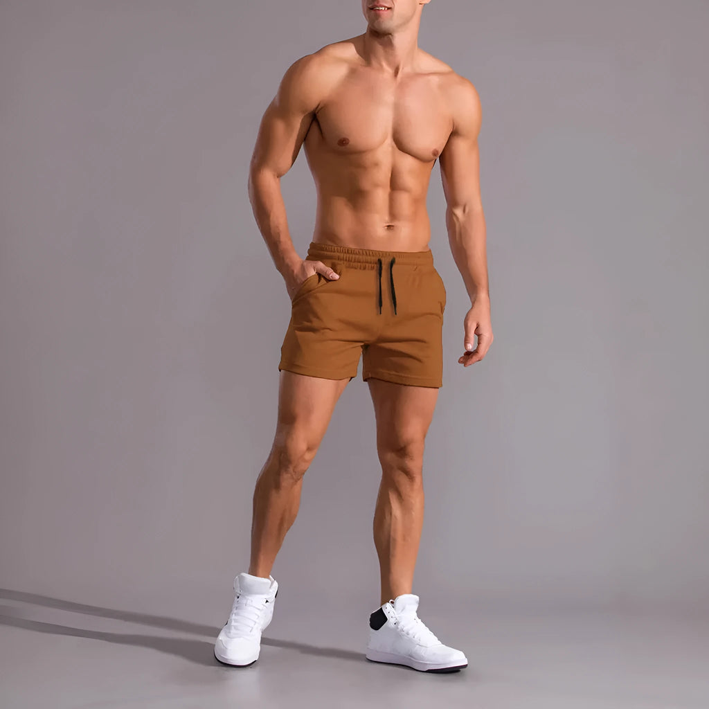 Three pairs of men's solid colour drawstring shorts in black, khaki, and light brown laid flat