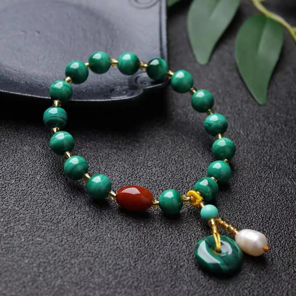 Natural green malachite bracelet with barrel-shaped beads on a wrist.