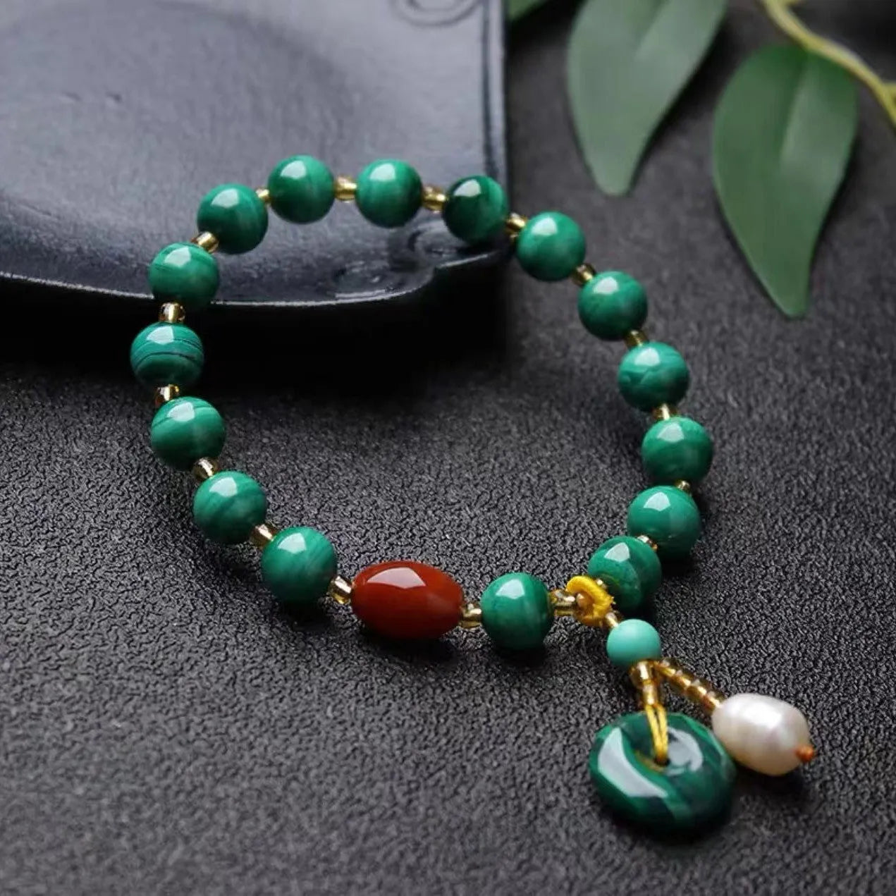 Natural green malachite bracelet with barrel-shaped beads on a wrist.
