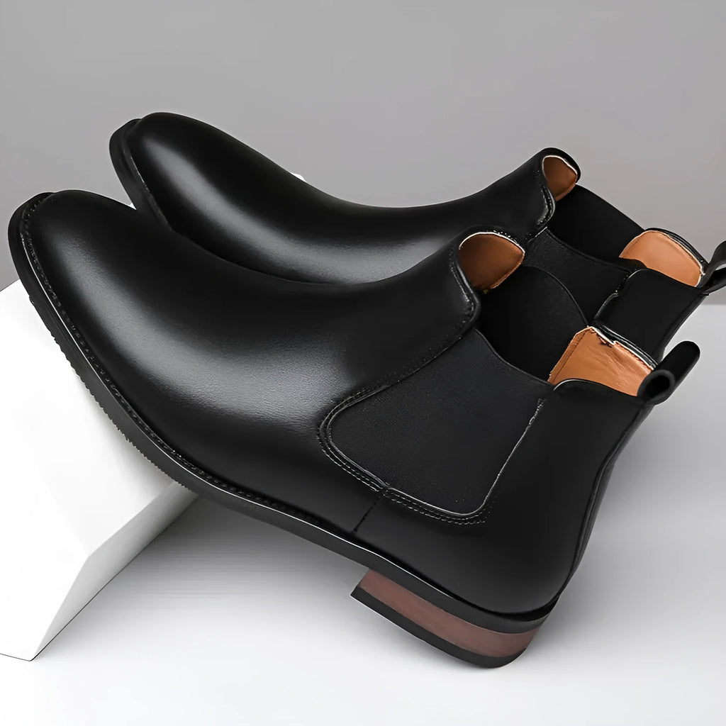 Men's black pointed-toe Chelsea boots with a high-top design and rubber sole on a white background.