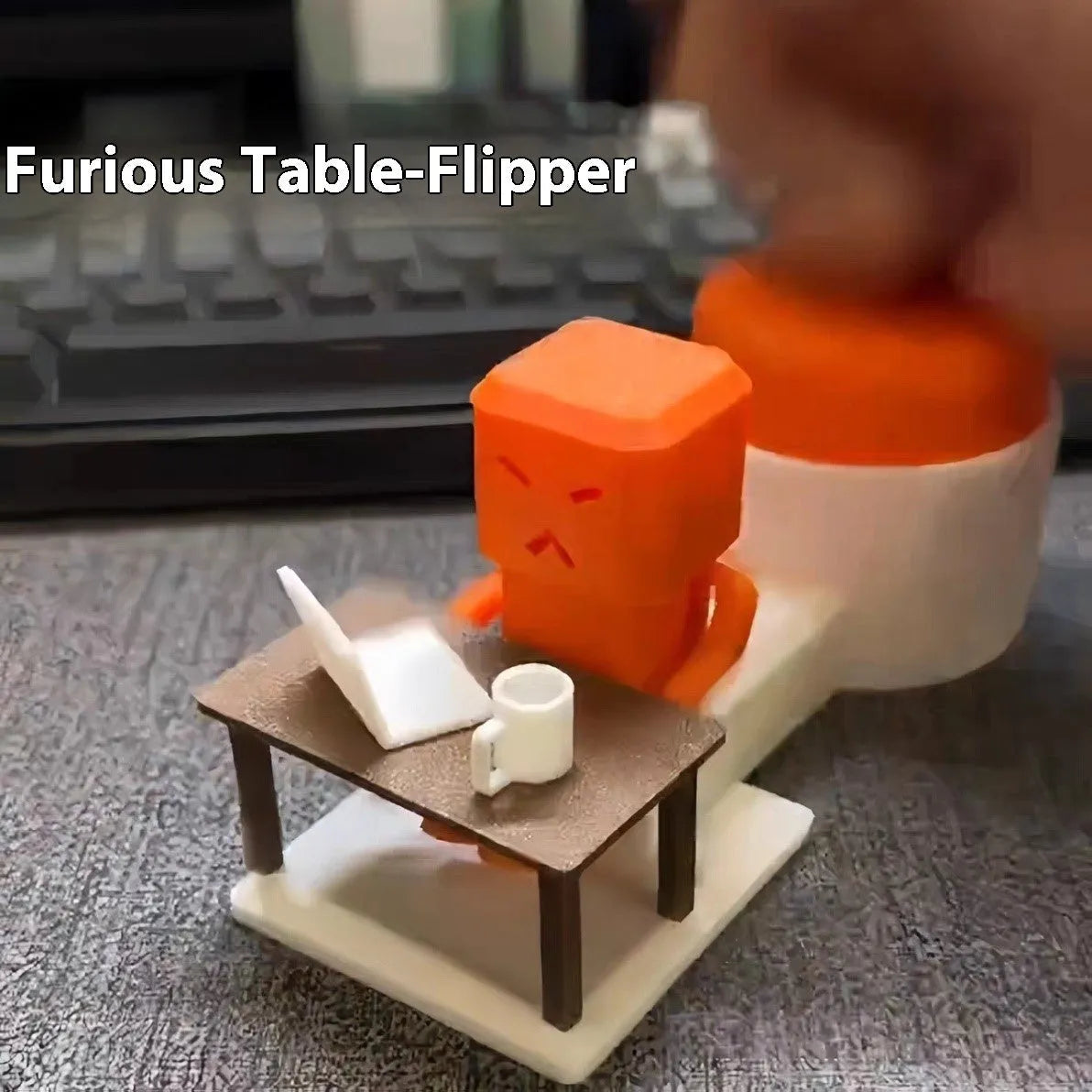 Orange plastic decompression toy with a table-turning mechanism on a desk.